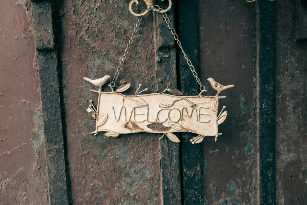A rustic metal welcome sign with bird decorations, perfect for home decor or entryways.