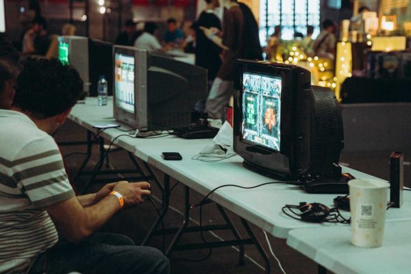 Adults enjoying a retro gaming event with CRT televisions and consoles, creating a nostalgic atmosphere indoors.