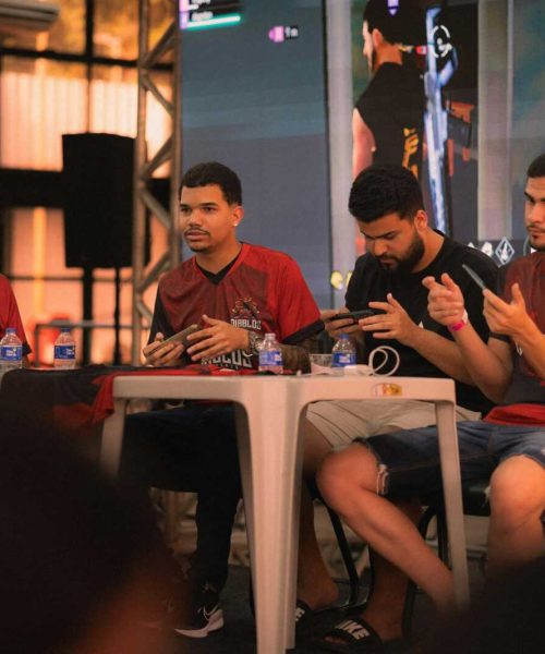 A group of e-sports players participating in a gaming event, focused on smartphone gameplay.