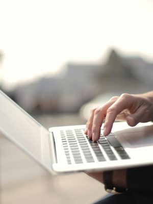 A business professional typing on a laptop in an outdoor setting, symbolizing remote work.