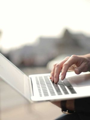 A business professional typing on a laptop in an outdoor setting, symbolizing remote work.